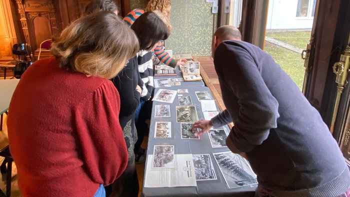 Students looking at photographs on a table at NIOD